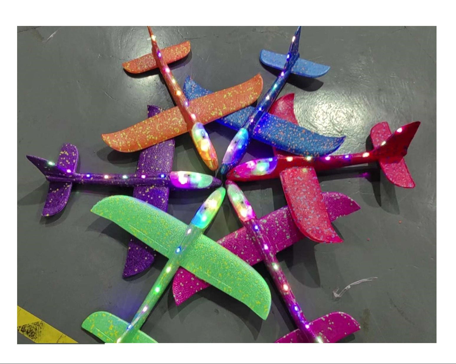 Colorful LED toy planes on a dark surface with text indicating dimensions and light feature.